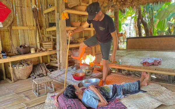 Photo d'un Akha pratiquant un massage au feu, une des activités bien-être traditionnelles Akha en Thaïlande.