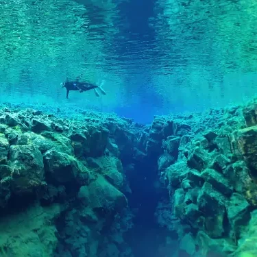 Une personne fait du snorkeling dans la faille de Silfra en Islande